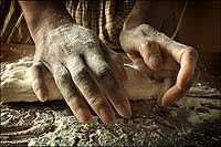 The flour-sprinkled hands of Gene Mitchell knead dough.