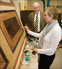 Shelley Svoboda cleans a panel in the conservation lab as Ronald Hurst looks on.