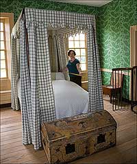 Curator Emily Roberts takes the measure of a bed.