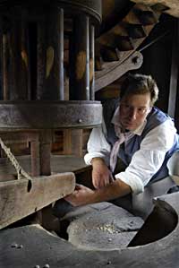 Interpreter Edward Schultz at the gears, hopper, and millstone. 