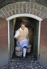 Rob Brantley of the foodways staff brings buckets of ice from the ice house.