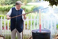 Weaver Max Hamrick dips wool into a bubbling kettle of cochineal dye.